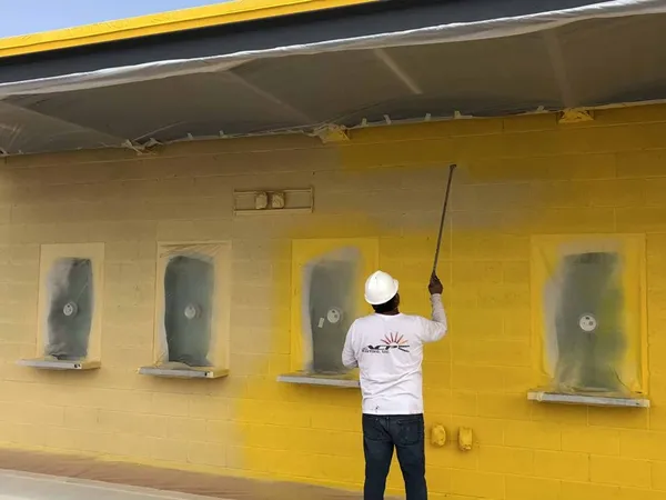 ACP Painting crew member painting a commercial exterior wall in Arizona heat