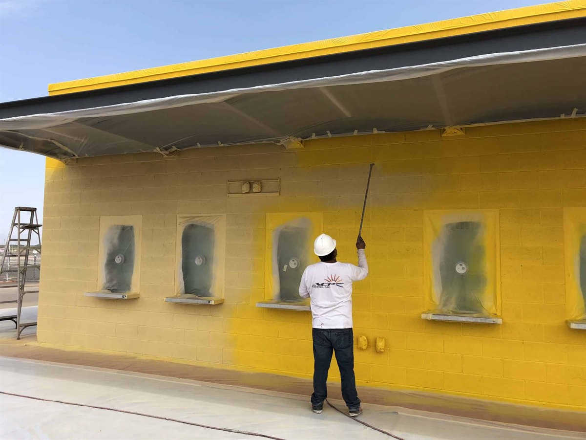 Commercial exterior wall being painted in Arizona heat by an ACP Painting crew member