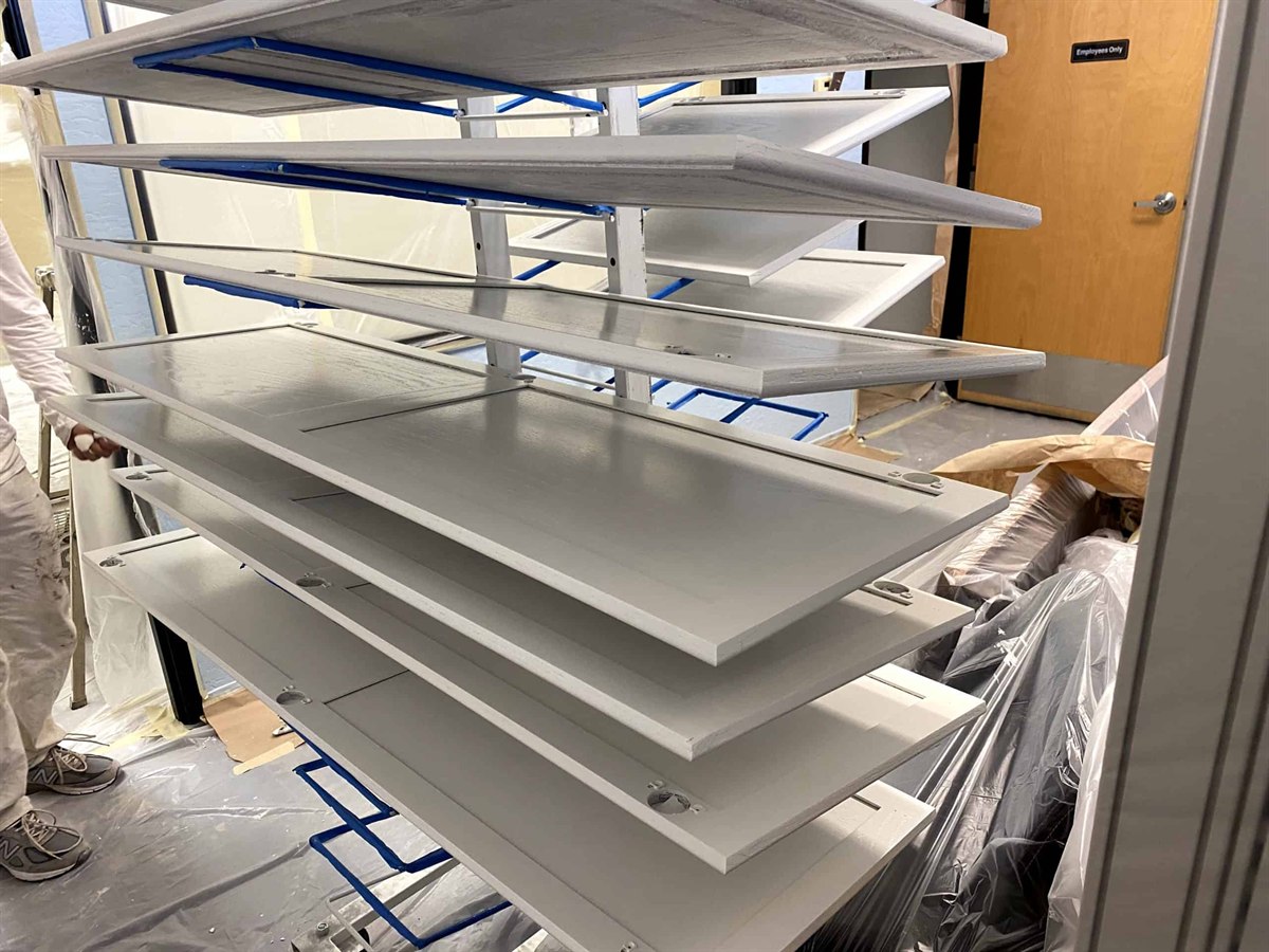 Freshly sprayed kitchen cabinet doors drying on racks at ACP Painting