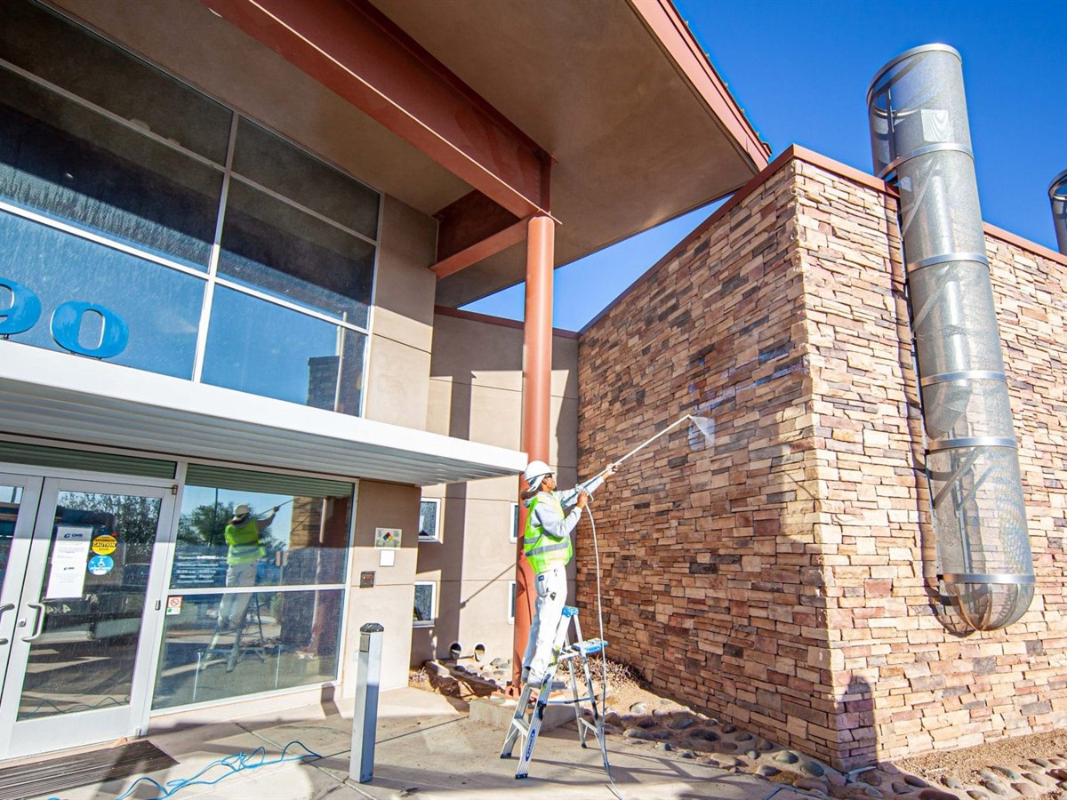 ACP Painting crew member prepping a retail storefront exterior for repainting
