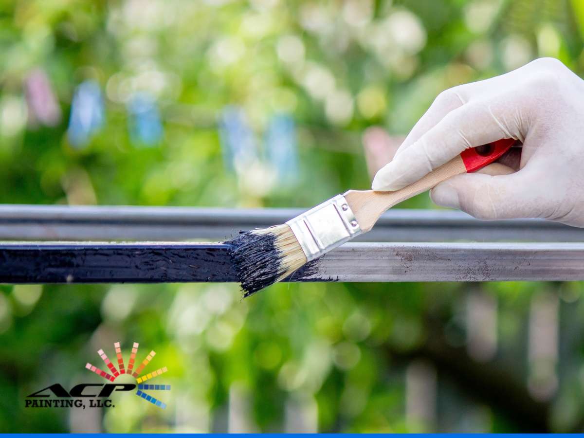 A hand wearing a white glove applies black paint to a metal bar with a brush, showcasing the services of Maricopa painting contractors specializing in metal protection.