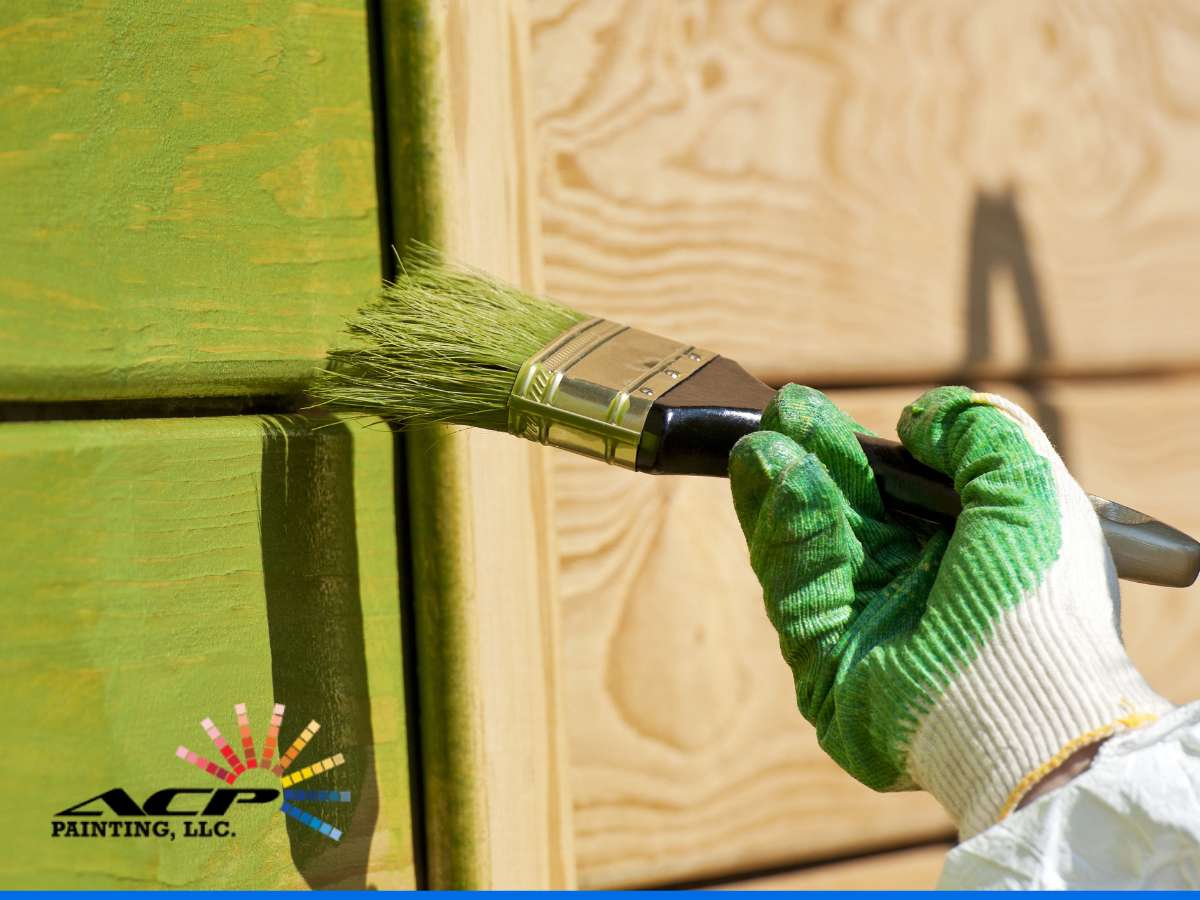 Close-up of a hand applying green Paint For Residential Exterior with a brush