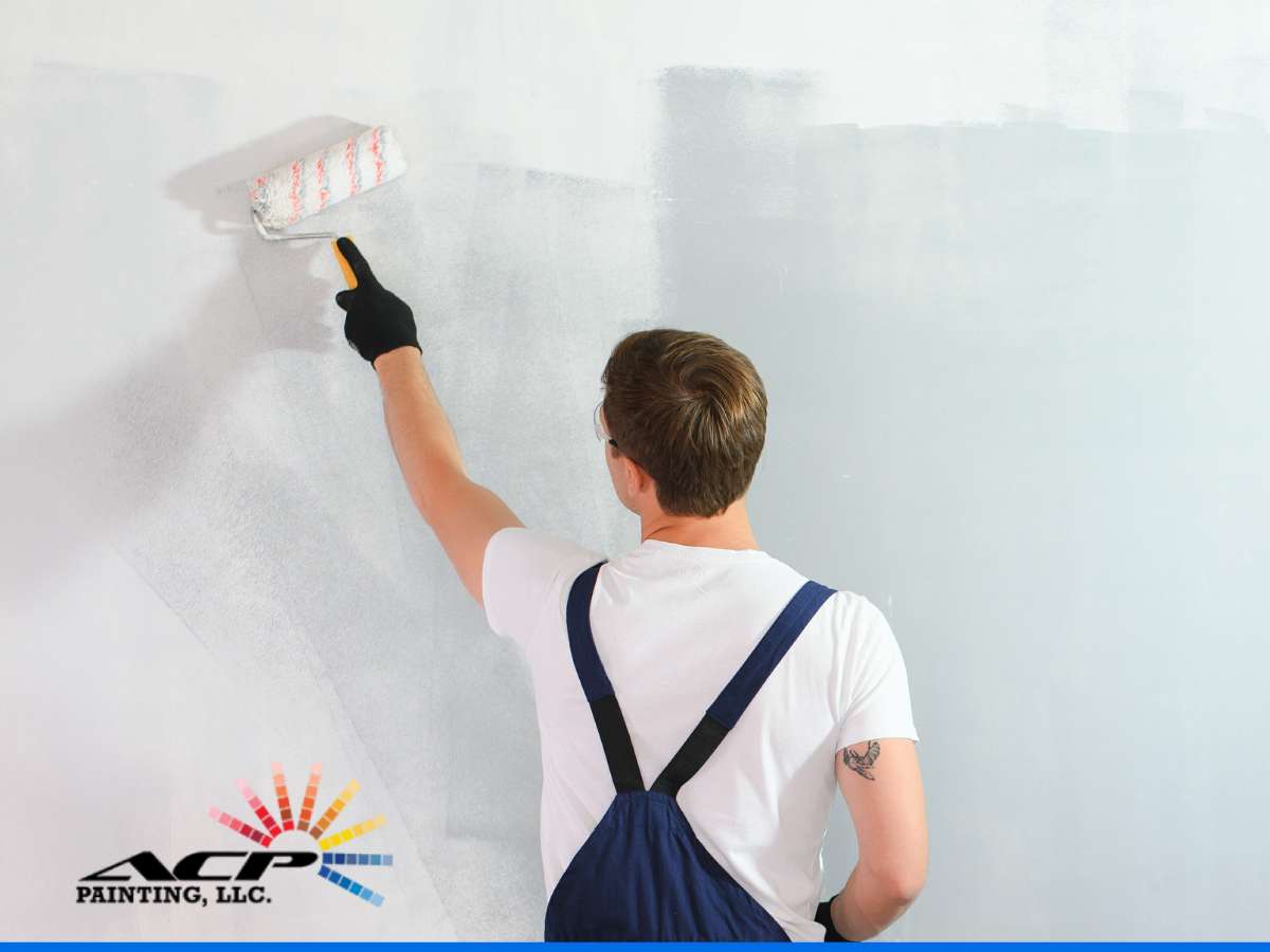 Painter applying a fresh coat of paint to a wall, focusing on Repainting for improved aesthetics and maintenance