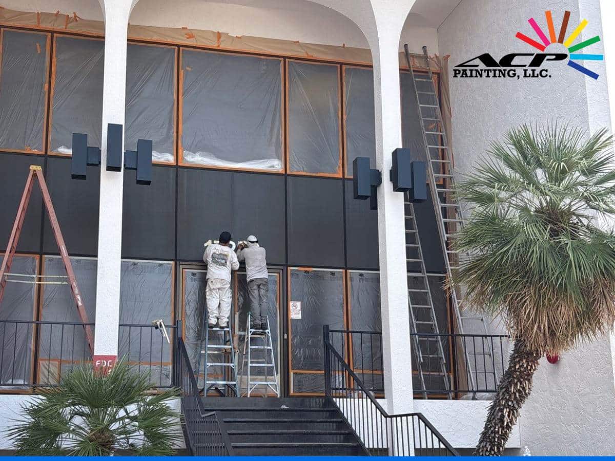 Professional painters working on the exterior of commercial buildings with ladders and safety precautions